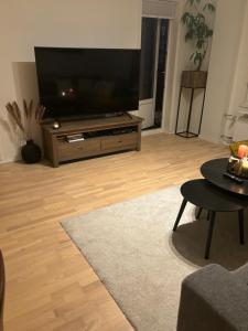 sala de estar con TV de pantalla plana grande en Fin leilighet nært alt en Bergen