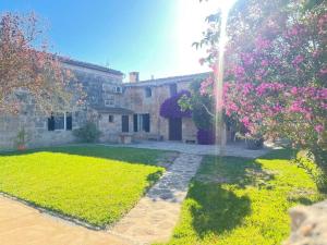 a house with a yard with a tree with pink flowers at Bonita casa de campo típica Mallorquina in Sant Jordi