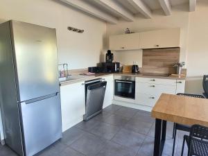 a kitchen with white cabinets and a stainless steel refrigerator at DUNES - Villa Patio Avec Jardin - proche Plage de la Gravière in Soorts-Hossegor