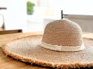 un cappello di paglia seduto sopra un tavolo di legno di Costa Inn Beach House with Pool by Homeful Homes a Costa da Caparica
