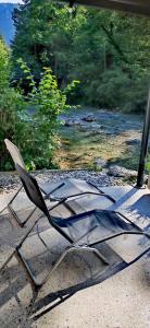 a metal chair sitting on the ground next to a river at Riverside Guesthouse in Ig