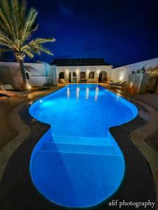 a large swimming pool with blue lighting at night at Maison Leila chambres d hotes in Midoun