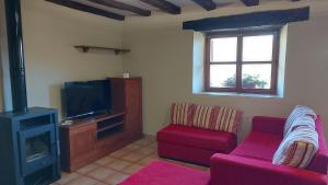 a living room with a red couch and a tv at La casa de Omi in Camaleño
