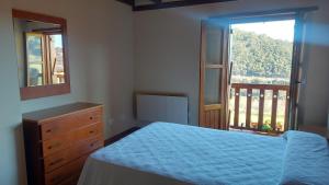 a bedroom with a bed and a dresser and a window at La casa de Omi in Camaleño