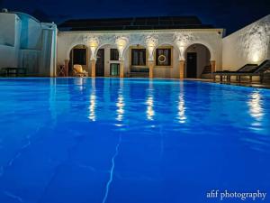 uma grande piscina à noite com iluminação azul em Maison Leila chambres d hotes em Midoun