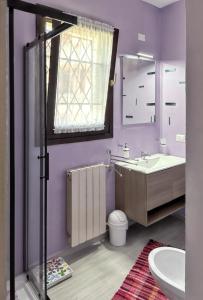 La salle de bains est pourvue de murs violets, d'un lavabo et d'un miroir. dans l'établissement 2 bedrooms apartement with sea view furnished terrace and wifi at Olbia 5 km away from the beach, à Olbia