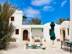 a white house with a patio with a table and chairs at Maison Leila chambres d hotes in Midoun