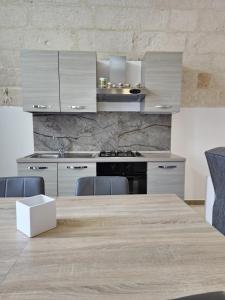 eine Küche mit weißen Schränken und einem Holztisch in der Unterkunft Poggio Fiorito in Porto Cesareo
