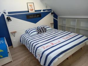 Un dormitorio con una cama con rayas azules y blancas. en Maison 100m de la plage les pieds dans l'eau, en Surtainville