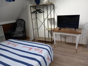 Un dormitorio con una cama, un escritorio y un televisor. en Maison 100m de la plage les pieds dans l'eau, en Surtainville