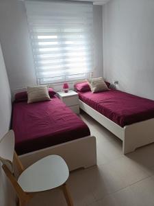 Un dormitorio con 2 camas y una ventana con sábanas moradas. en Casa Bedoll, en Miami Platja 32 fotos más