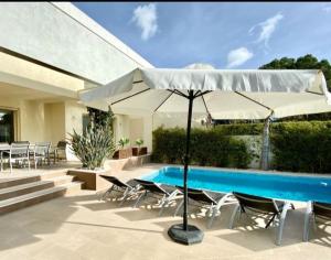a patio with a pool and an umbrella and chairs at Vistamar in Les tres Cales