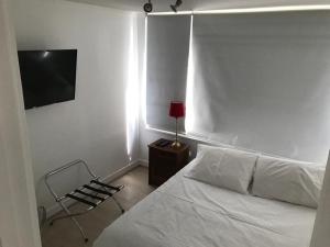 1 dormitorio con 1 cama, 1 silla y TV en Kennedy Premium Apartments II en Santiago