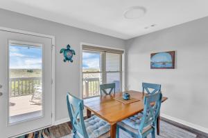 a dining room with a wooden table and chairs at Slow Motion #8A in Topsail Beach