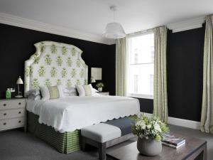 a bedroom with a large bed with a floral headboard at Haymarket Hotel, Firmdale Hotels in London