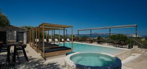 a swimming pool with a hot tub and tables and chairs at Altamar Hotel in Pefki