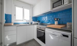 a kitchen with white cabinets and blue tiles at R155 - Apartamento Frente al Mar en Coma-Ruga 2 in Comarruga