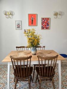 a dining room table with chairs and a vase of flowers at Nid douillet Cosy T2 quartier haut centre-ville in Sète