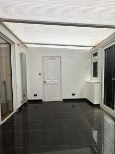 an empty room with a white door and a tile floor at Home Apartments Stay in Abbey Wood +6 photos