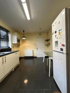 a kitchen with a refrigerator and a table in it at Home Apartments Stay in Abbey Wood