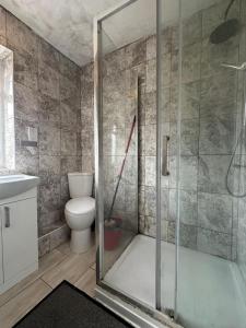 a bathroom with a toilet and a glass shower at Home Apartments Stay in Abbey Wood