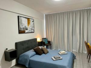 1 dormitorio con cama azul frente a una ventana en FatCow Seaside Suites, en Livadhia