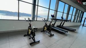a gym with three exercise bikes in a room with windows at JQ Unity Homestay 2 High Floor Seaview Netflix 6pax in Kota Kinabalu