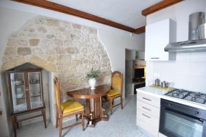 a kitchen with a table and a stone wall at B&B CASAVACANZE CHIESA MADRE in Carovigno