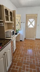 a kitchen with a brown tiled floor and a door at Sunset Flats - Aconchengante Flat na Rua Pituba bem perto das Praias Urbanas! Itacare BA - PIT 1 in Itacaré