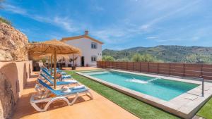 a swimming pool with lounge chairs and an umbrella at Villa Los Ruedos Riogordo by Ruralidays in Ríogordo