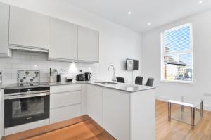 a white kitchen with a sink and a stove at Access West Kensington in London