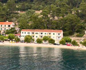 a building on a beach next to the water at Apartmani Grubiša in Drvenik