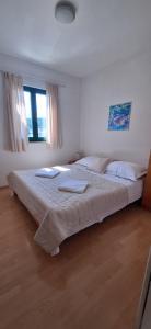a bedroom with a large bed with two towels on it at Apartmani Grubiša in Drvenik