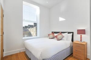 Un dormitorio blanco con una cama y una ventana. en Access West Kensington, en Londres