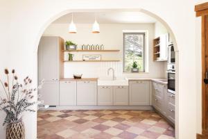 an archway in a kitchen with white cabinets and a sink at Gîte Glycine pour 8 personnes avec sauna et bain nordique in Capian +34 photos