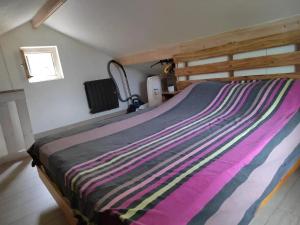a bedroom with a bed with a striped blanket on it at Chalet confortable à Varces-Allières-et-Risset avec terrasse in Risset