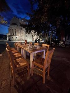 une table et des chaises en bois avec un bâtiment en arrière-plan dans l'établissement Vosinakis House in Volos, à Vólos