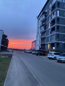 an empty street with cars parked next to a building at Авторський ремонт Апартаменти біля Щасливого,поруч озеро in Rivne