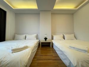2 camas en una habitación con sábanas blancas en 日日藍旅市區民宿, en Hualien City