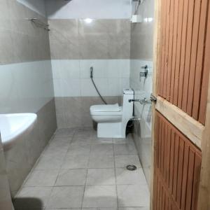 a bathroom with a white toilet and a sink at Mother's eco lodge in Jibhi