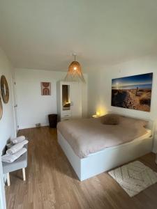 een witte slaapkamer met een groot bed en een stoel bij appartement Axelle 2 in Blankenberge