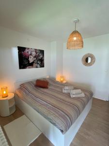 een groot bed in een witte kamer met 2 lampen bij appartement Axelle 2 in Blankenberge