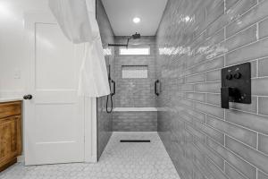 y baño con ducha y pared de azulejos blancos. en JK'S Bungalow in Waco, en Waco 13 fotos más