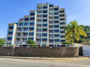 a tall building with palm trees in front of it at Apartamentos Playa Dorada in Pampatar