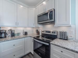 een keuken met witte kasten en een kookplaat oven bij Strand Bungalow in Surf City +31 foto's