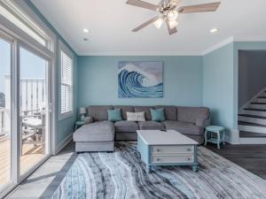 een woonkamer met een bank en een plafondventilator bij Strand Bungalow in Surf City