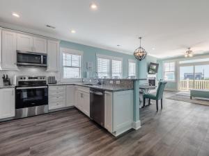 een keuken met witte kasten en een eetkamer met een tafel bij Strand Bungalow in Surf City