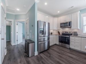 een keuken met witte kasten en een roestvrijstalen koelkast bij Strand Bungalow in Surf City
