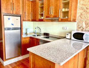 a kitchen with wooden cabinets and a stainless steel refrigerator at Casa Varela en Noia in Noya +6 photos