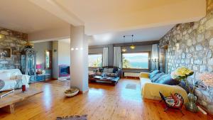 a living room with a couch and a stone wall at Panorama Villa Sea view in Selianitika